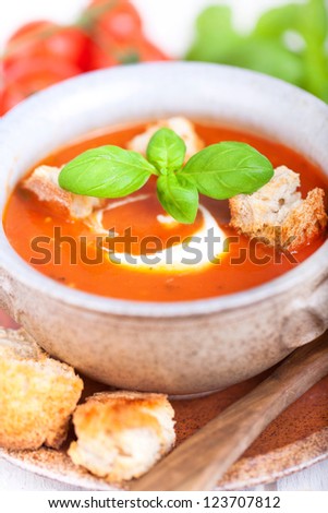 fresh diet tomato soup with basil thyme and raw tomatoes with bread pieces in a bowl on white background, ready to eat