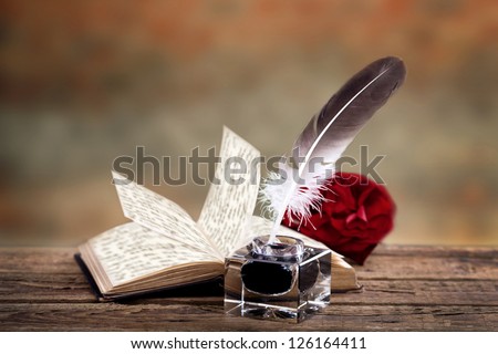 old book with a rose, feather and ink bottle isolated on white background, feather pen and inkwell