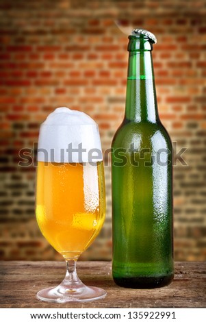 Frosty fresh beer with foam in a glass and in a bottle with rustic background