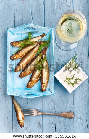 fresh smoked sprats on a tray with fresh herbs and mayonnaise and a glass of white wine, ready for diner, bird\'s-eye view