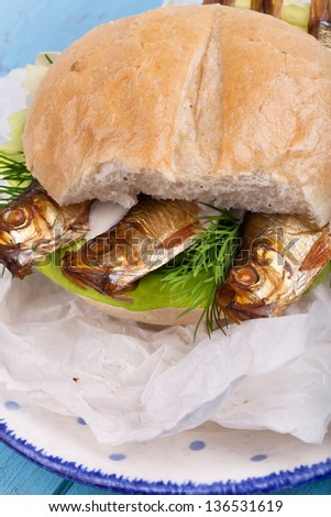fish bread roll with sprats and salad on a plate