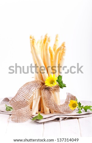 white asparagus bunch with a yellow flower on a white wooden board isolated on white