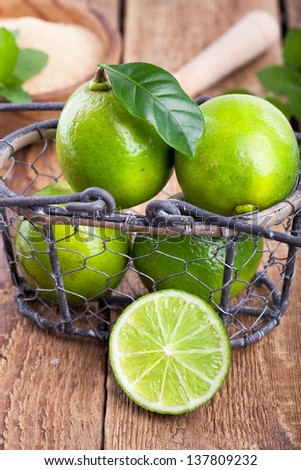fresh lime fruit in a wire basket on rustic wooden table