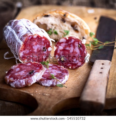 Salami with homemade Ciabatta and herbs on rustic wooden board