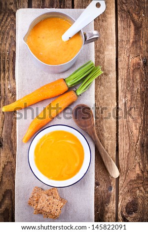 fresh carrot soup on old wooden table, bird`s eye view