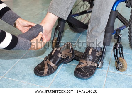 helping a disabled Young man in wheelchair get dressed