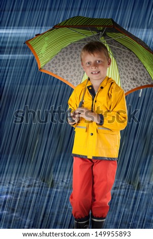 happy Young Boy with colorful raincoat and umbrella outside in the rain
