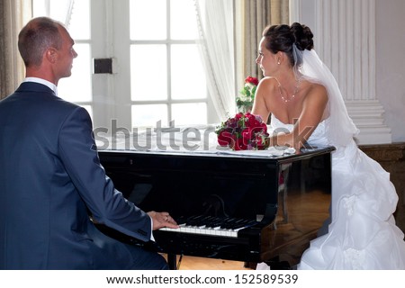 bridal couple on wedding day, groom is playing piano for his bride