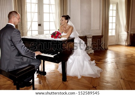 Beautiful couple on their wedding day, groom playing piano for his bride in an amazing castle
