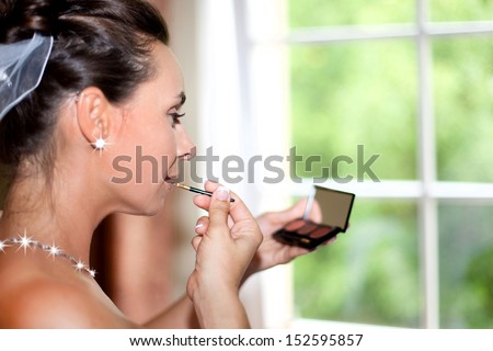 Young beautiful bride applying wedding make-up, Beautiful bride applying lip-gloss in the mirror