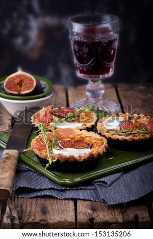 fresh tart or pie with figs, ham, goat cheese and thyme, served with a glass of red wine