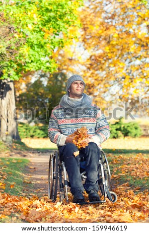 handicapped man in an autumn park sitting in his wheelchair enjoying the peace of being out in nature amongst the colorful yellow trees