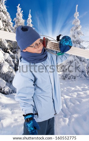 Young Boy with skiing Equipment on winter landscape, little boy is focused on preparing for skiing