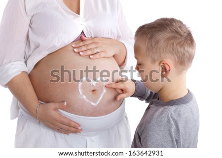 pregnant woman with her son, he is painting a heart on her belly, isolated on white