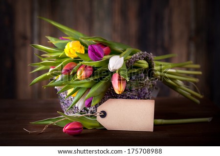 colorful easter tulips in a basket with empty tag for your text