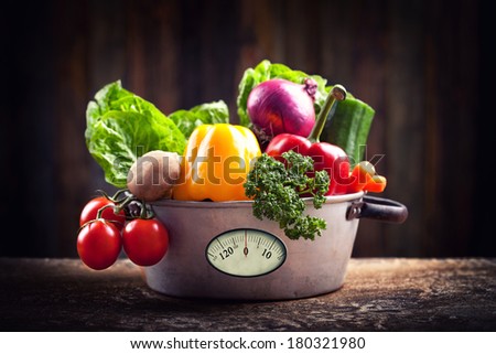 fresh vegetables in rustic pot with weight scale on dark Background, mystic light