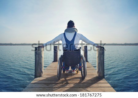 disabled Young man in wheelchair on a boardwalk on lake enjoying his freedom