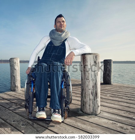 young handicapped man in a wheelchair watching the sea in spring