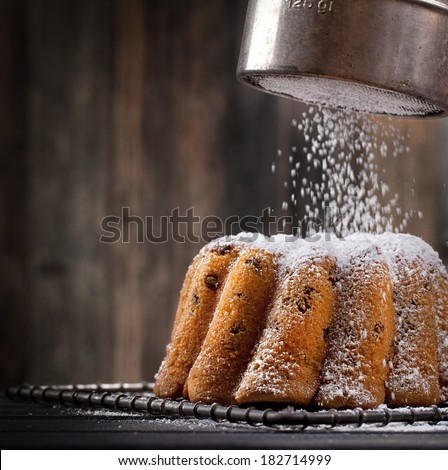 icing sugar falling on a freshly baked sweet cake, dark background