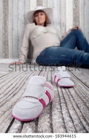 newborn shoes for the baby with pregnant mother in background
