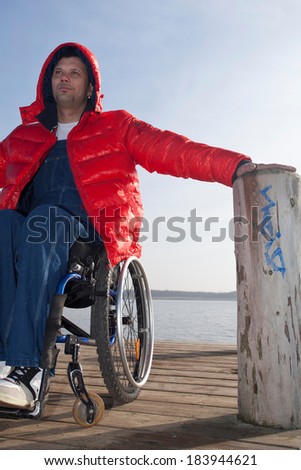 handicapped man in wheelchair on boardwalk at a lake