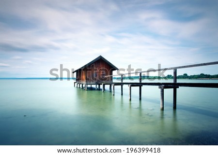landscape with an old wooden house at the lake in summer, long time exposure