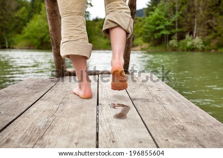 man walk barefoot feet on old wooden Pier on a lake in bavarian alps, he leaves a wet footprint