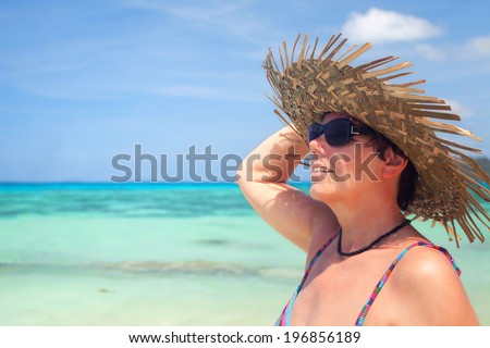 best aged woman on the beach with sun hat and sun glasses enjoys the sun