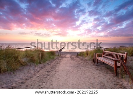 old wooden bench to rest on access to the beach, sunset at a beach of Baltic sea on summer evening