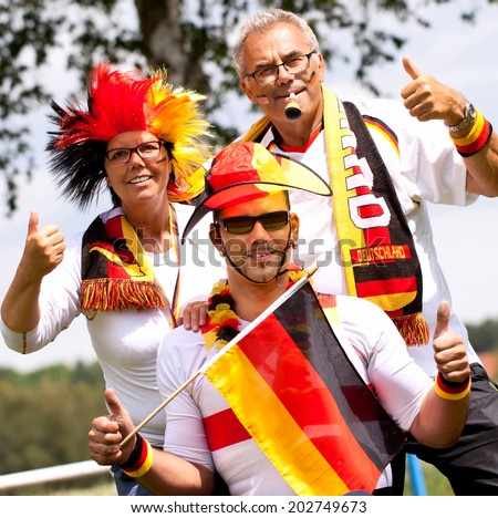 three German soccer fans support their Team, cheering German fans with flag, scarf and hat