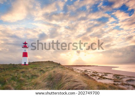 beautiful sunset landscape at the North sea with a lightning lighthouse, the Island of Sylt, Germany