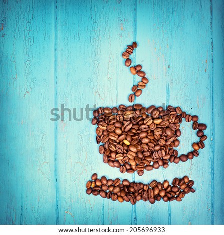 cup from coffee beans with fresh roasted beans on blue wooden background