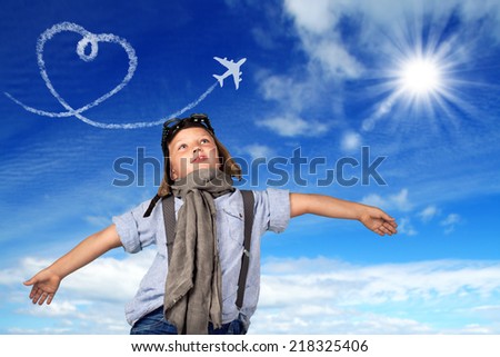 Beautiful smiling child in helmet on a blue background playing with a plane. Vintage pilot (aviator) concept