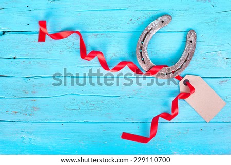Horseshoe and a vintage tag with red ribbon on blue wooden table, happy new year concept