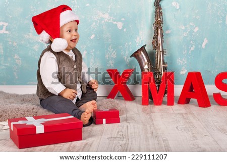 cute Little Baby boy in red santa hat with christmas presents sitting on the floor with Christmas decoration