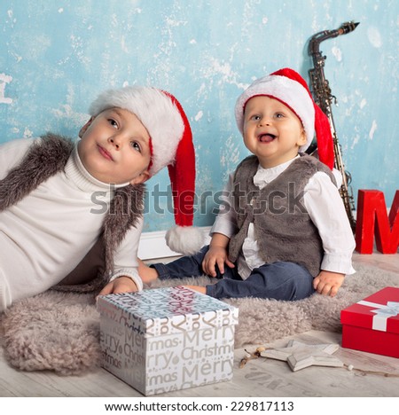 Kids in red santa hat with their christmas presents presents sitting and lying on the floor