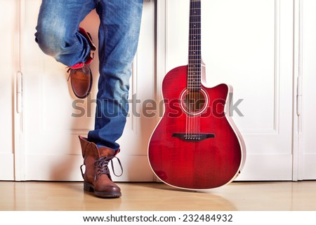 red guitar standing on White wooden door in Addition to the legs of stylish guitarist