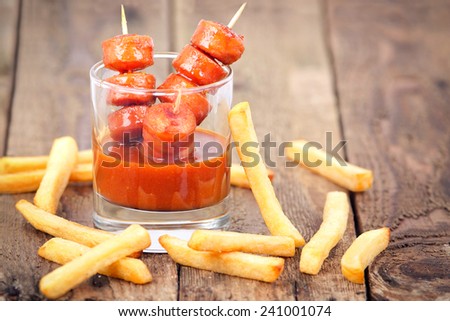 Curry sausage  served in a glass, with french fries on wooden board