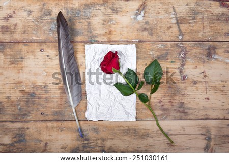 love letters, sentimental vintage background with antique paper, red rose and feather pen on old wooden background