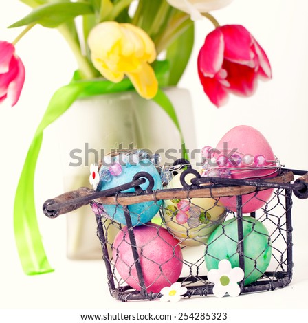 5 colorful easter eggs on basket with fresh tulips in Background, isolated on white