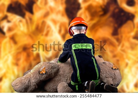 little boy in firefighter uniform save the teddy from the flames