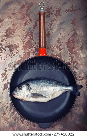 fresh sea bream fish in an old pan on rustic sheet in an old kitchen