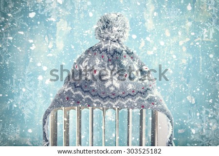 hat on a radiator / heater on a blue cold winter background