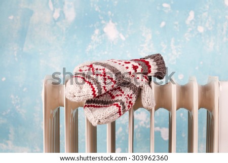 gloves on a radiator / heater on a blue cold winter background