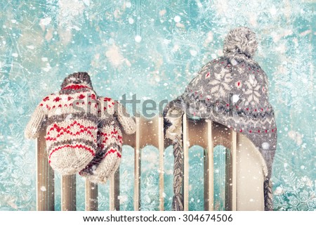 hat and gloves on a radiator / heater on a blue cold winter background