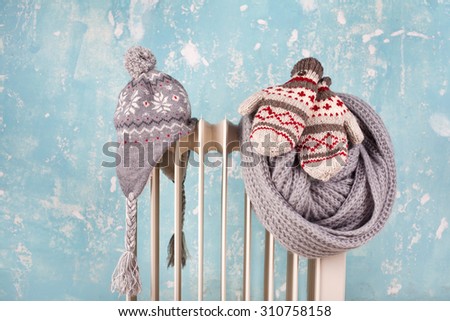 hat and gloves on a radiator / heater on a blue cold winter background