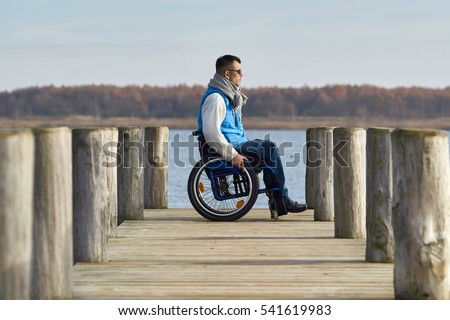 handicapped man with wheelchair outside in nature