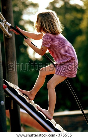 female caucasian child climbing up a wooden climbing frame
