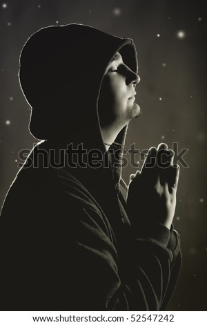 Hooded man praying to God