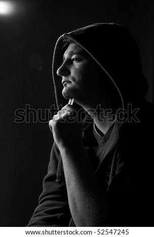 Hooded man sticking a razorblade to his neck